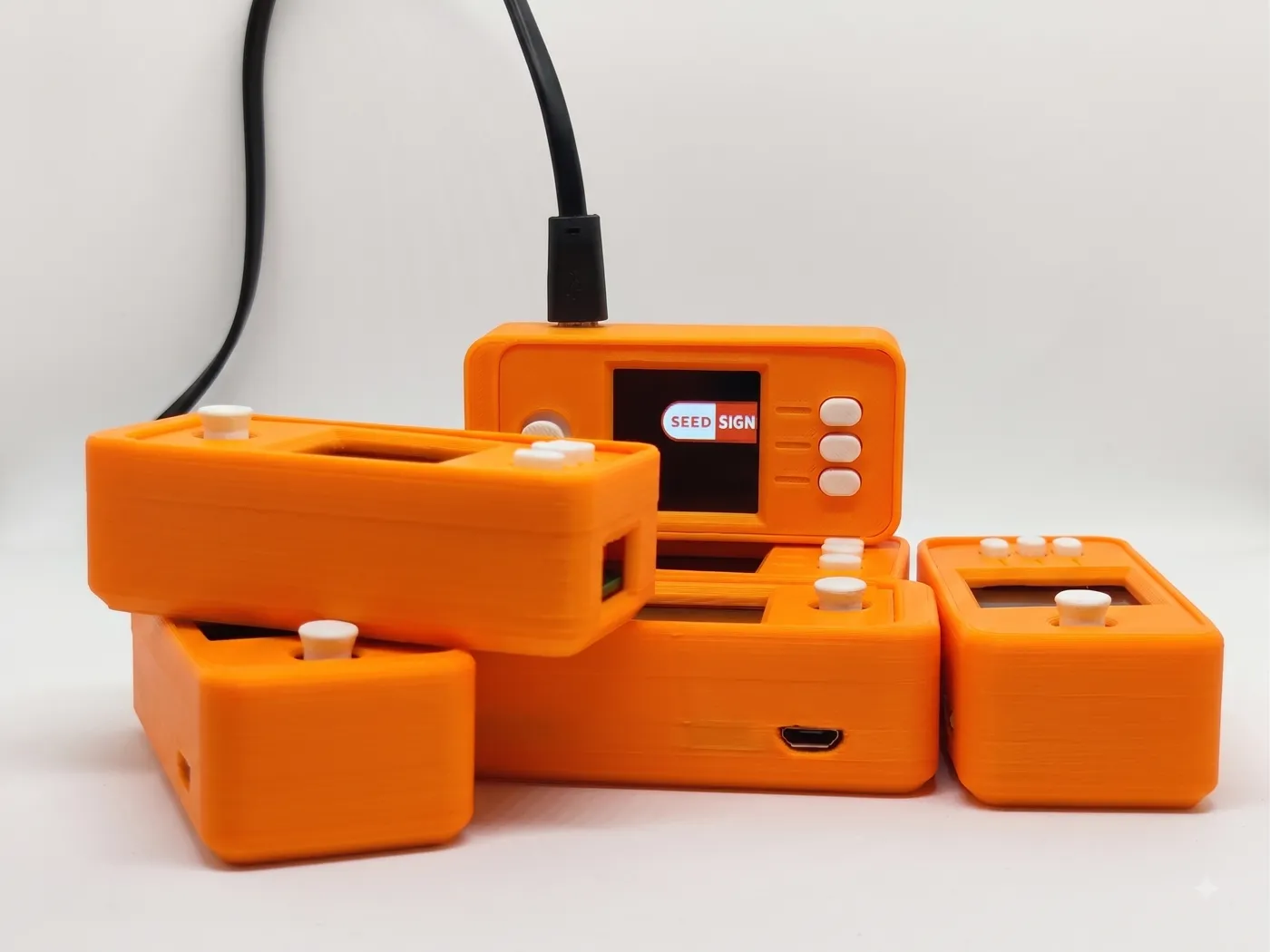 Six orange SeedSigner devices stacked, one showing the SeedSigner logo